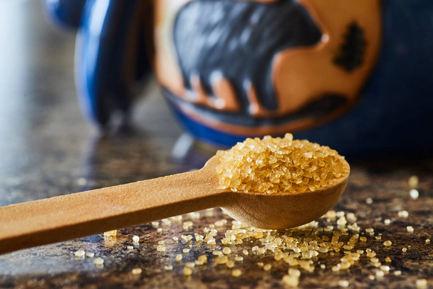 Close-up of golden brown sugar crystals on a wooden spoon, in a rustic kitchen setting in Fort Wayne, Indiana - perfect for baking and natural foods - Photo, Image