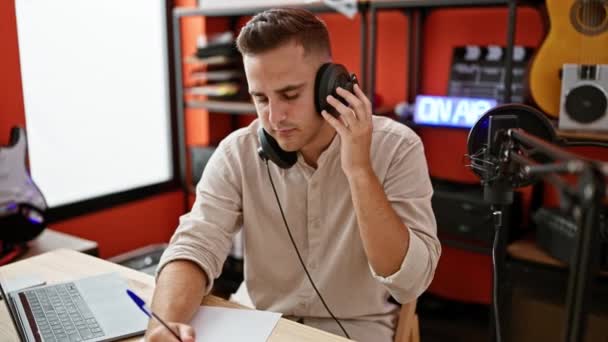 Hombre enfocado con auriculares escribiendo en estudio de música. - Imágenes, Vídeo