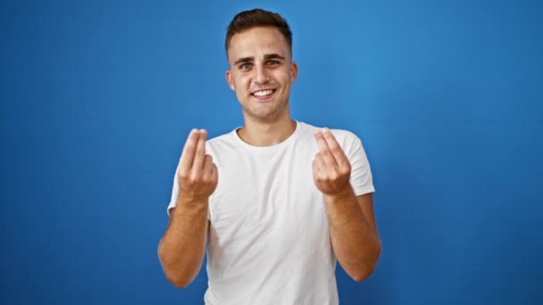 Mosolygó fiatal felnőtt férfi gesztikulál kezével ellen elszigetelt kék háttér visel fehér ing - Felvétel, videó