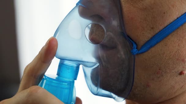 Nebulizör maskeli sağlıksız bir adamın evde nefes alışını yakından izleyin. Sağlık, tıbbi ekipman ve insan konsepti. Yüksek kalite 4k görüntü - Video, Çekim