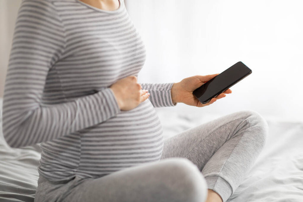 Uma visão de perto de uma grávida europeia ladys mãos e barriga, evocando conectividade e o conforto de casa durante a gravidez - Foto, Imagem