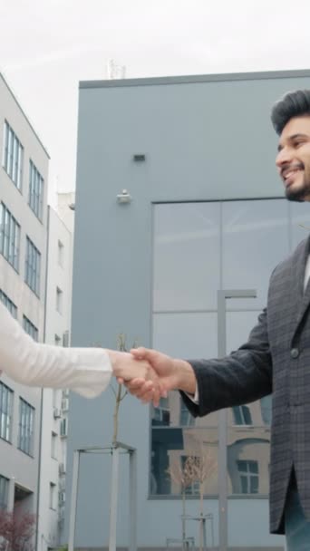 Vertical Screen: Happy arabian man and woman shaking hands after successful cooperation while standing near modern office building. Concept of people and teamwork. Man and woman shaking hands. - Footage, Video