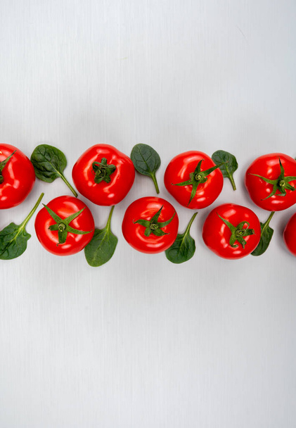 Пищевой орнамент, красные спелые вкусные голландские помидоры и листья шпината, здоровые овощи задний план вид сверху, копировальное пространство - Фото, изображение