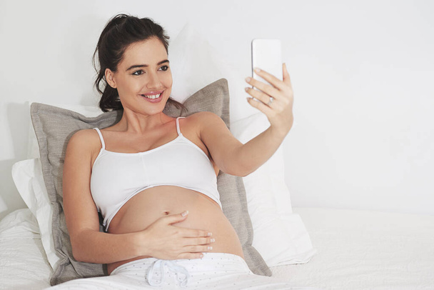 Щаслива вагітна жінка, селфі або відеодзвінок в домашній спальні для спілкування або онлайн-консультації. Посмішка, мама або горда мати на мобільному додатку для гінекології телездоров'я, оновлення вагітності або материнства. - Фото, зображення