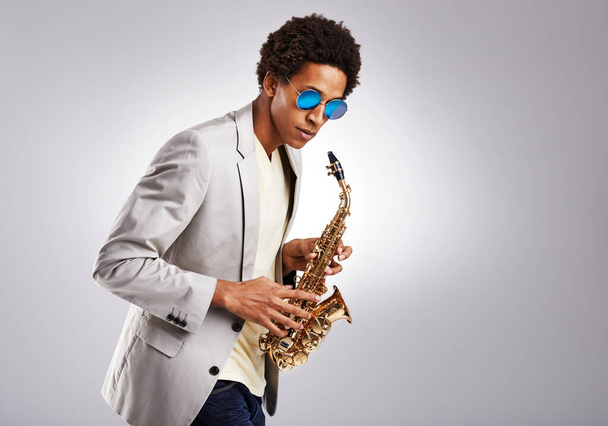 Saxophone, black man and sunglasses with jazz artist, creative and expression on grey studio background. Person, musician or model with instrument and classic genre with hobby, melody and performance. - Fotó, kép
