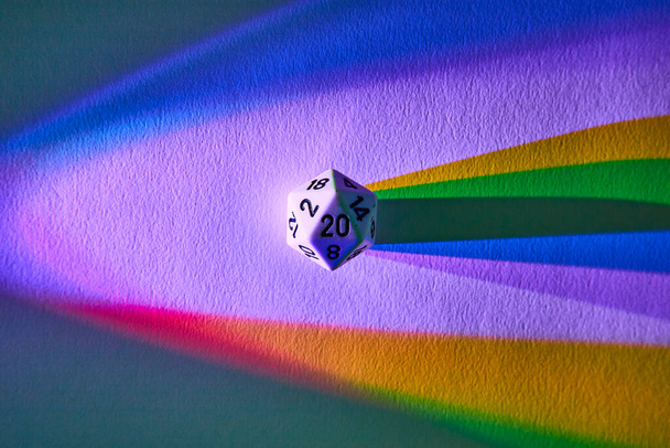 Жесткий отбрасывающий радужную тень, 20-гранный кубик символизирует шанс и разнообразие в этом абстрактном макрокадре из Форт-Уэйна, Индиана. - Фото, изображение