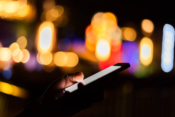 Frau hält nachts Handy mit weißem Bildschirm in der Hand - Foto, Bild