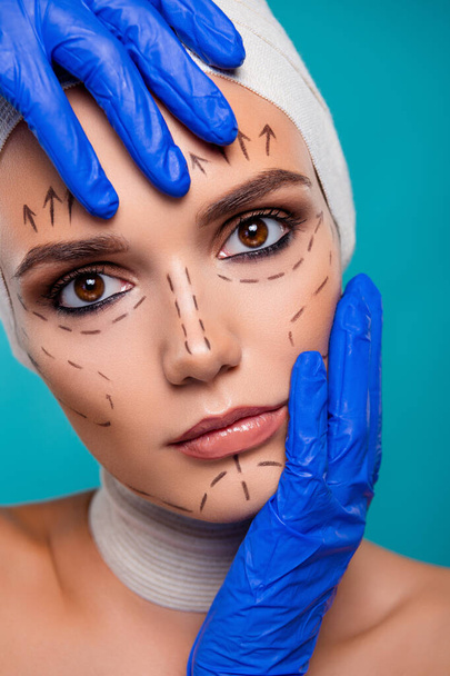 Крупным планом фото женщины, касающейся лица врачом руки готовятся к операции красоты изолированы на голубом фоне. - Фото, изображение