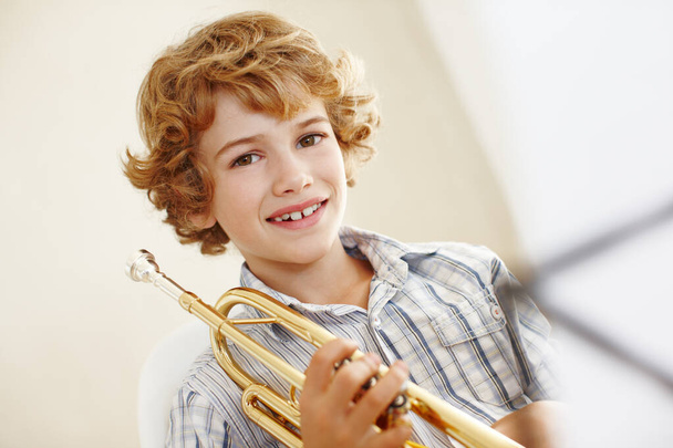 Χαμόγελο, μουσική και πορτραίτο παιδιού με τρομπέτα για μάθηση, μάθημα ορχήστρας και εξάσκηση στο talent show. Μουσικός, δημιουργικό χόμπι και χαρούμενο νεαρό αγόρι με όργανο, φύλλο και νότες για να παίξει το τραγούδι. - Φωτογραφία, εικόνα