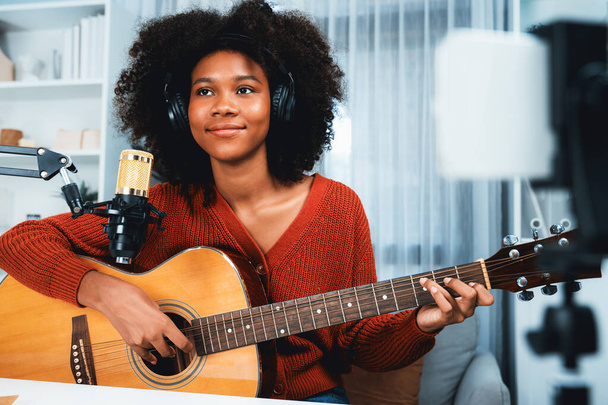 Host csatorna gyönyörű afrikai nő befolyásoló énekel gitározni broadcast stúdióban okostelefonon. A zenei blogger idősávja az élő közösségi médián. Koncepciója audio készítő. Kóstoló. - Fotó, kép