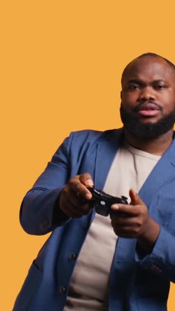 Vertical video Gamer annoyed after losing online multiplayer videogame, being defeated by rivals. Man doing facepalm in frustration after seeing game over message, holding controller, studio - Footage, Video