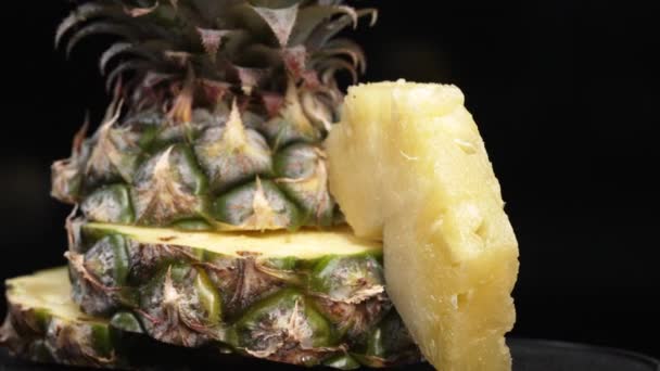 Close-up video van verse ananas met schijfje schil ananas insert met gescheiden zwarte achtergrond. De ruwe en wasachtige korst, met een kroon van stekelige groene bladeren, Food fotografie. Bestanddelen. - Video