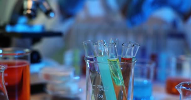 Modernes Labor mit Gläsern unterschiedlicher Form mit Proben. Chemiker in Handschuhen nimmt Reagenzglas mit Flüssigkeit in Zeitlupe - Filmmaterial, Video