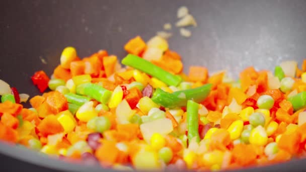 Renkli kesilmiş sebzeler ahşap bir kaşık ile karıştırılıyor. Sebzeler pişerken cızırdar ve aromatik kokular yayar.. - Video, Çekim