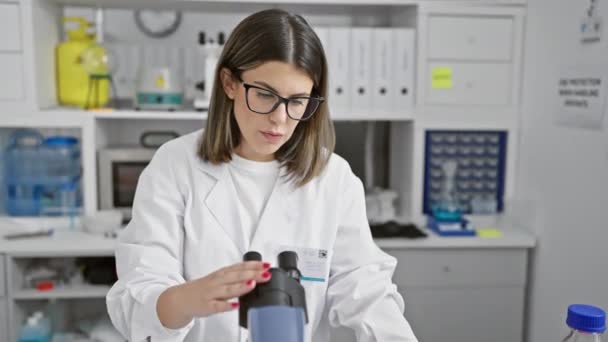 Συγκεντρωμένη γυναίκα επιστήμονας που χρησιμοποιεί μικροσκόπιο σε κλινικό εργαστηριακό περιβάλλον, αντανακλώντας την έρευνα στον τομέα της υγείας. - Πλάνα, βίντεο