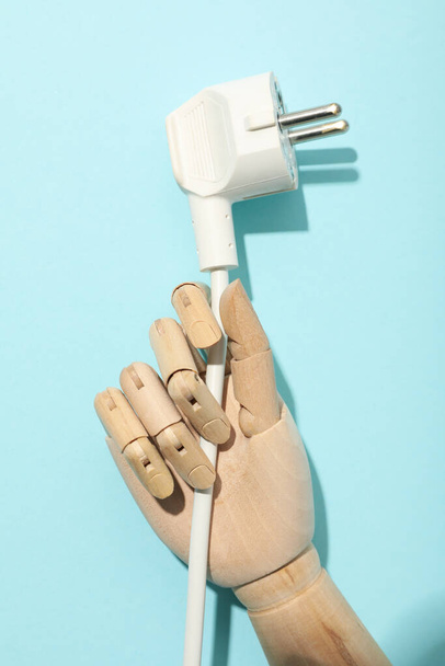 Electric cable in mannequin's hand on blue background - Photo, Image