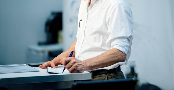 Бизнесмен в своем офисе, под гипсом синего цвета, подписывает важный бизнес-контракт. - Фото, изображение