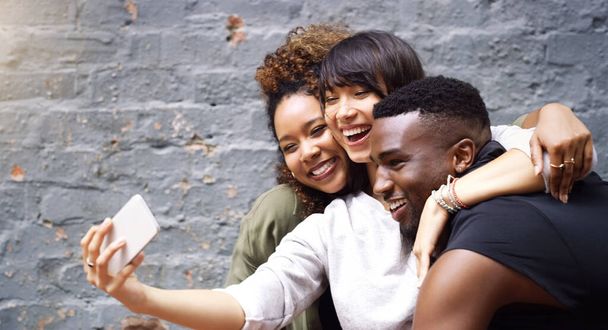 Selfie, social media and smile with friends on brick wall background for profile picture update. App, energy or excitement with happy man and woman group in city for mobile or online photography. - Photo, Image
