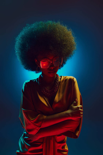 Portret van jonge, mooie vrouw, artistiek zangeres poserend in retro kleding in neon licht tegen gradiënt achtergrond. Concept van kunst, muziek, hobby, klassieke muziek en moderne levensstijl. Steun - Foto, afbeelding