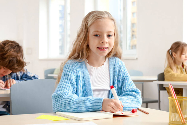 Retrato de menina da escola sorrindo tomar notas na aula enquanto olha para a câmera. Conceito de educação. De volta à escola - Foto, Imagem