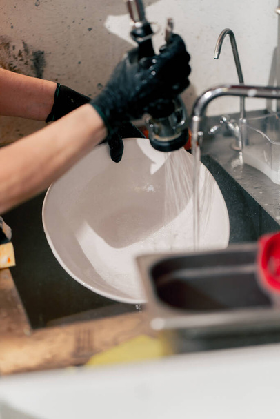 primo piano di una donna che lava i piatti sporchi in cucina dopo aver utilizzato attrezzature professionali - Foto, immagini