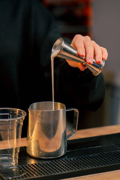 Κλείστε ένα νεαρό κορίτσι στο μπαρ ρίχνει την απαιτούμενη ποσότητα αλκοόλ με το κύπελλο μέτρησης σε ένα κοκτέιλ - Φωτογραφία, εικόνα