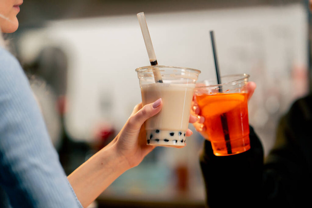 közeli kép egy narancssárga gép csomagolására italok műanyag egy bárpulton egy lány használja a gépet - Fotó, kép