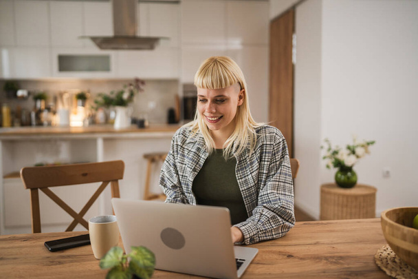 Junge kaukasische Blondine arbeitet am Laptop von zu Hause aus glücklich positiv - Foto, Bild