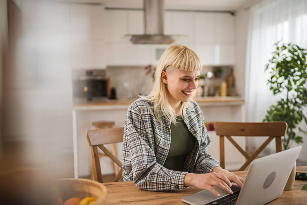 Jeune femme blonde caucasienne travailler sur ordinateur portable de la maison heureux positif - Photo, image