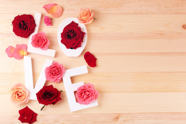 Beautiful roses with word LOVE on wooden background - Fotografie, Obrázek