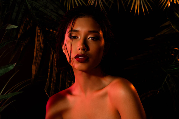 Фото азиатской корейской девушки с макияжем посмотрите под неоновым оранжевым светом. - Фото, изображение