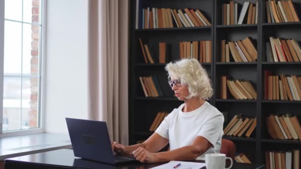 Старшая женщина средних лет расслабляет руки и тело, отдыхая от работы на ноутбуке. Пожилая зрелая женщина счастлива после работы, удовлетворенная хорошим результатом. Усталость от длительного использования ноутбука - Кадры, видео