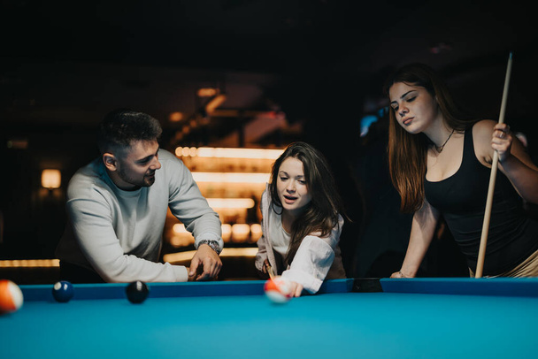 A group of friends focused on winning at pool in a casual, ambient setting. - Photo, Image