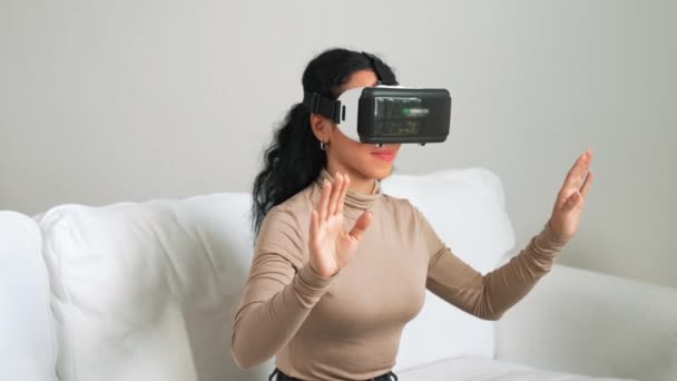 Jonge vrouw die virtual reality VR-bril thuis gebruikt voor cruciale online winkelervaring. De virtual reality VR innovatie geoptimaliseerd voor vrouwelijke digitale entertainment lifestyle. - Video