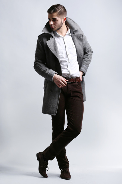 Jeune homme en manteau sur fond gris
 - Photo, image