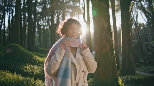 Girl standing forest sunlight in chic scarf exuding happiness and style closeup. Cheerful woman revealing in warm nature glow feeling content. Happy female traveler feeling serenity at vivid woodland - Footage, Video