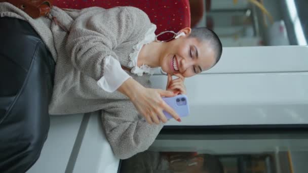Train passenger video calling by smartphone sitting wagon. Happy short hair woman smiling talking to cellphone camera vertical shot. Cute cheerful girl enjoy online phone conference awaiting departure - Footage, Video