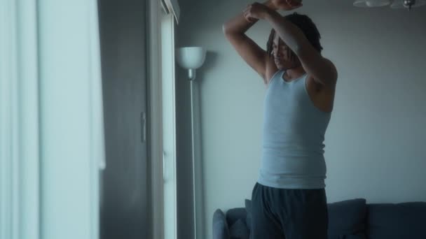 A man doing stretches next to a window at home. Healthy lifestyle and sport. Slow motion.  - Footage, Video