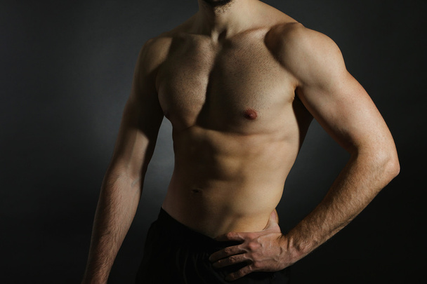 muskulöser junger Mann mit dunklem Hintergrund - Foto, Bild