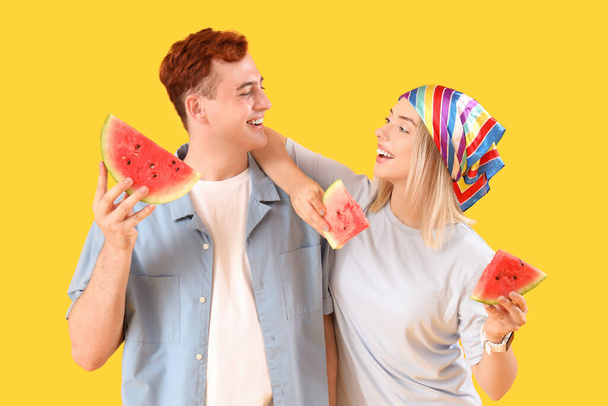 Jeune bel homme et femme avec des tranches de pastèque fraîche sur fond jaune - Photo, image