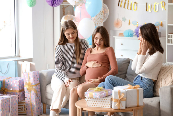 Jeune femme enceinte avec ses amis assis sur le canapé à la fête de la douche de bébé - Photo, image