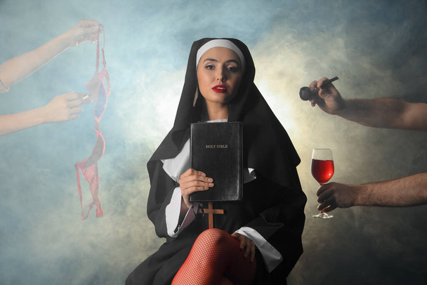 Непослушная монахиня со Священной Библией и дымом на темном фоне - Фото, изображение
