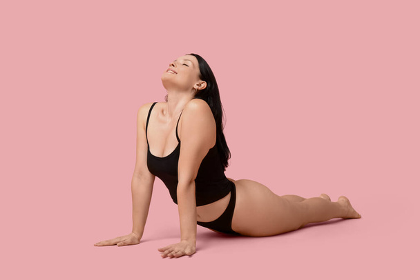 Body positive young woman in underwear lying on pink background - Photo, Image