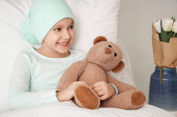 Pieni tyttö kemoterapian jälkeen lelukarhu makaa klinikalla. Kansainvälinen lasten syövän päivä - Valokuva, kuva