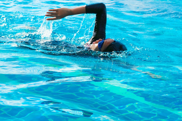 女性は標準的な水泳スタイルのフリースタイルで泳ぐ. - 写真・画像