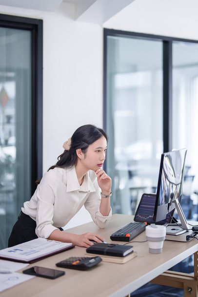 Investor businesswoman standing and reading business stock data on computer while working about stock and marketing of new startup to analysis trade and investment of business project in office. - Photo, Image