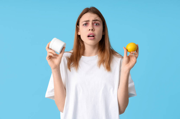 Nuori nainen, jolla on purkki kermaa ja sitruunaa, kärsii allergiasta sinisellä pohjalla - Valokuva, kuva