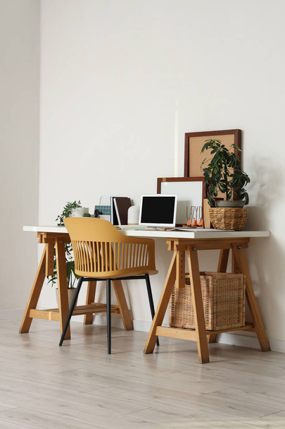 Interior de la oficina con cómodo lugar de trabajo, silla, plantas de interior y portátil moderno - Foto, imagen