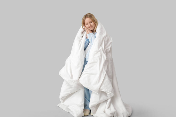 Adorable fille enveloppée dans une couverture dormant sur fond blanc - Photo, image