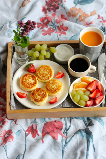 Сніданок у ліжку - сирники з чорною кавою, апельсиновим соком, сметаною та свіжими фруктами - Фото, зображення